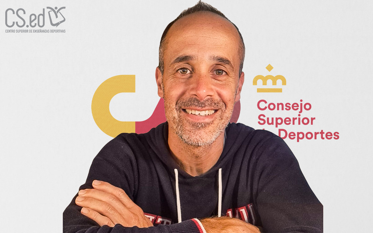 Retrato de un hombre con el pelo corto y oscuro, vestido con una sudadera con capucha azul oscuro, sonriente, fondo blanco con el logotipo del Consejo Superior de Deportes