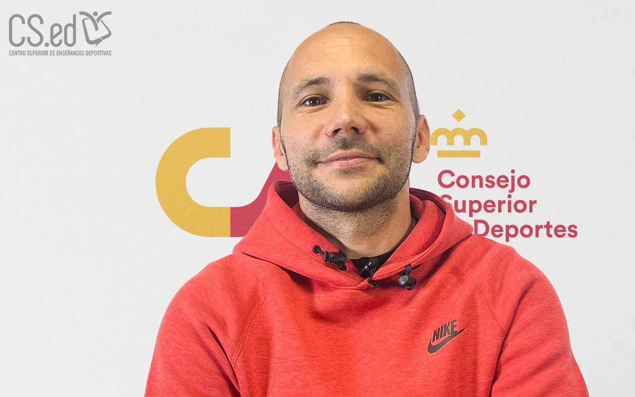 La imagen muestra a un hombre con barba mirando a la cámara. Lleva una sudadera roja con capucha. Detrás de él hay un logotipo del "Consejo Superior Deportes"